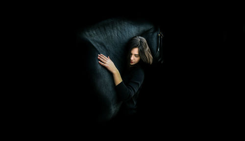 Portrait of a young woman against black background