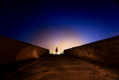 Man flashing light towards sky at night