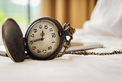 Close-up of pocket watch on bed