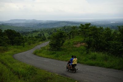Rear view of man riding bicycle on road against sky