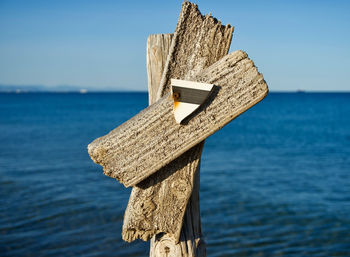 Close-up of wooden post by sea against sky