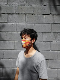 Man wearing mask standing against wall