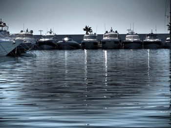 Boats moored in calm sea against clear sky