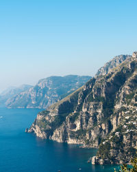 Scenic view of sea and mountains against clear blue sky