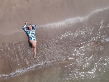 Drone view of woman lying on shore at beach