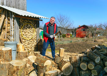 Spring landscape with a man in a red vest, a man in his yard splits firewood,