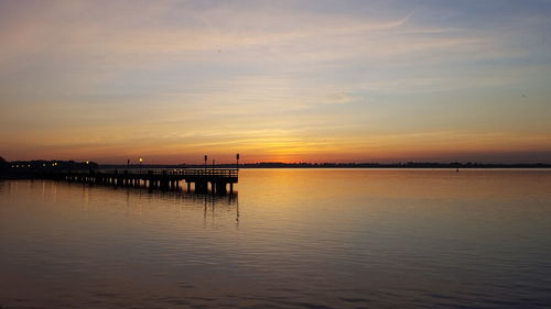 View of pier in sea at sunset