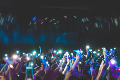 Large group of crowd cheering by flashing lights at music concert