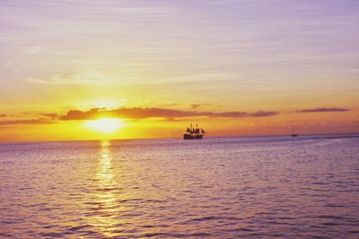 Silhouette boat sailing in sea against sky during sunset