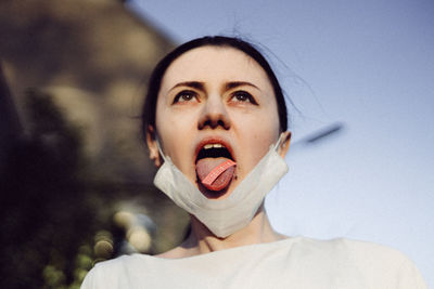 Close-up of woman sticking out tongue while wearing mask