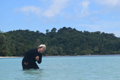 Side view of young woman against trees against sky