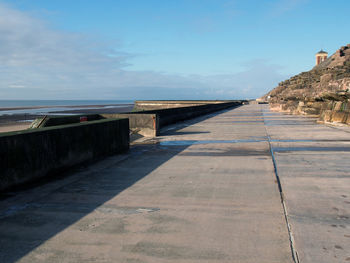 Footpath by sea against sky