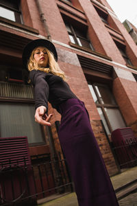 Low angle portrait of woman standing against building