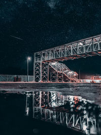 Illuminated bridge over river against sky at night