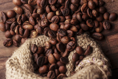 High angle view of roasted coffee bean spilled from jute bag