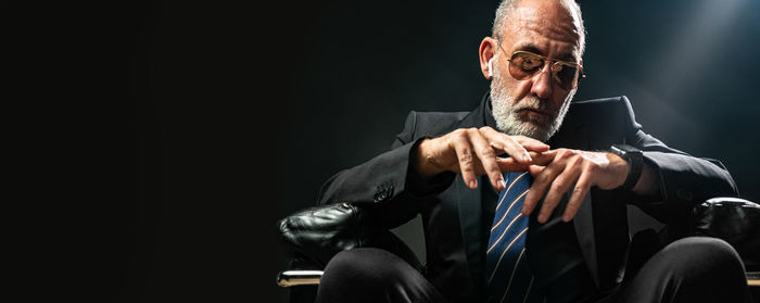 Low angle view of man sitting against black background