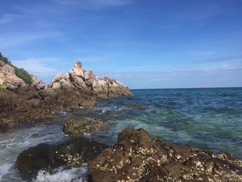 Scenic view of rocks in sea against blue sky