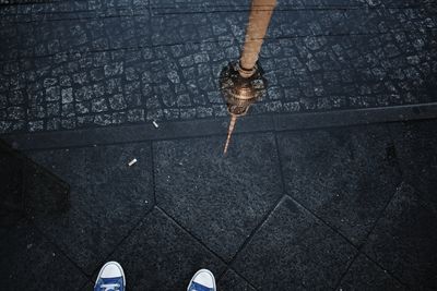 Low section of person on street with reflection of fernsehturm on puddle