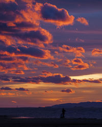 Silhouette people on beach against sky during sunset