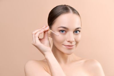 Close-up of young woman against pink background