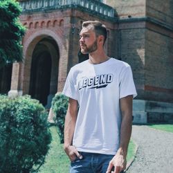 Young man looking away while standing against built structure