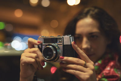 Mid adult woman taking photograph at night