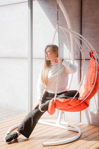 Side view of young woman sitting on table