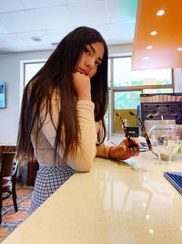 Portrait of young woman using phone on table