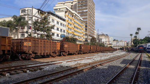 Railroad tracks in city against sky