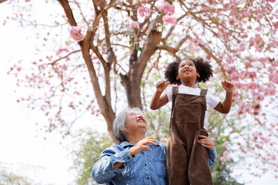 Portrait of a smiling young woman sitting on cherry tree