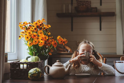 Girl drinking tea on table at home