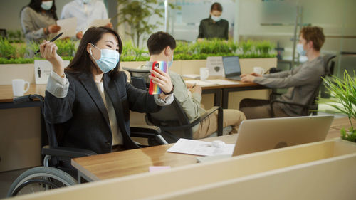 Businesswoman wearing mask talking on video call in office