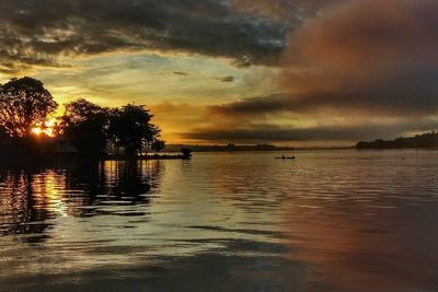 Scenic view of lake against cloudy sky during sunset
