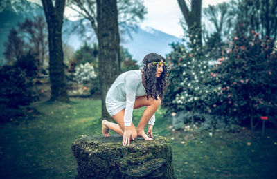 Full length of young woman on rock in forest