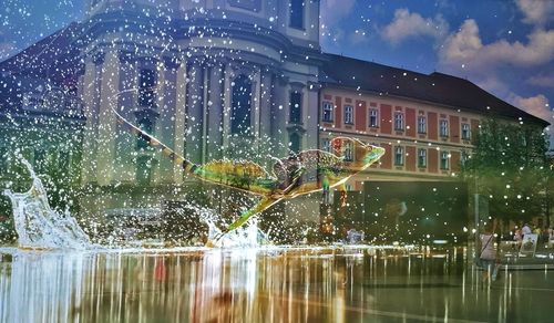 Water splashing on fountain in city against sky