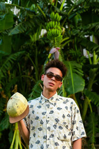 A young guy wearing summer clothing. palm tree as background.