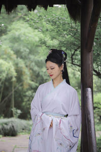 Young woman standing against trees