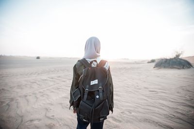 Rear view of young woman standing on snow covered landscape