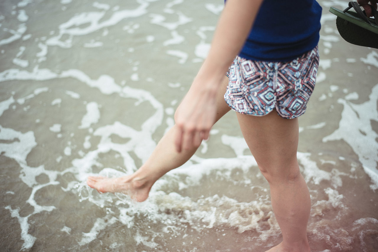 water, low section, person, lifestyles, leisure activity, barefoot, standing, beach, wet, shore, childhood, casual clothing, high angle view, human foot, sand, outdoors, day