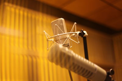 Close-up of microphones in recording studio seen through glass