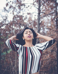 Young woman with hand in hair standing at forest