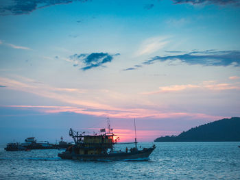 Boat in sea against sky during sunset