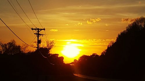 Silhouette of electricity pylon at sunset
