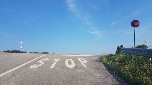 High angle view of stop text on road against blue sky