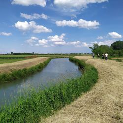 Scenic view of stream amidst field against sky