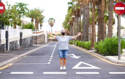 Full length of woman with arms outstretched standing on road