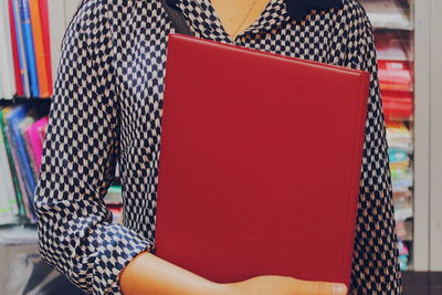 Midsection of woman holding red file
