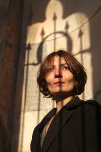 Portrait of a young woman standing against wall