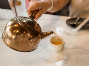 Pouring tea with a brass teapot in to the small cup