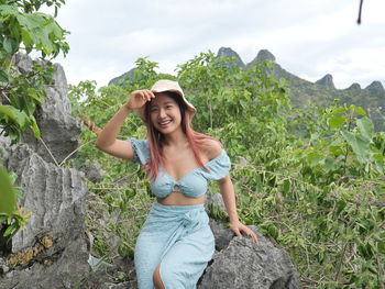 Side view of young woman standing against trees